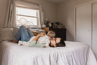 Anne, huzurlu bir yatak odasında bebeğine sarılıyor.