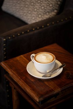 Masanın üzerinde köpüklü sütlü büyük kafe latte.