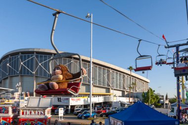 Stuffed plush monkey riding a ski lift at fairgrounds clipart