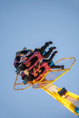 İnsanlar karnaval gezisinde havada baş aşağı duruyorlar.