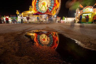 Long exposure of ferris wheel reflected in puddle clipart