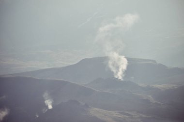 Gökyüzünün altında buharlı görkemli volkanik dağlar