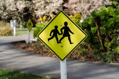 Bright yellow children crossing sign in park clipart