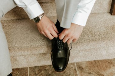 Damat siyah ayakkabı bağlamaya hazırlanıyor.