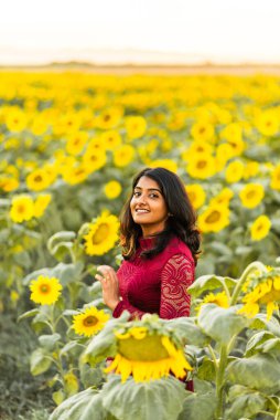 Kırmızı elbiseli bir kadın güneş batarken gülümsüyor..