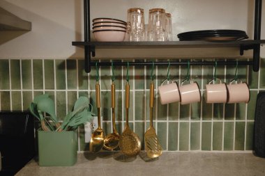 Kitchen countertop with utensils, mugs, and neatly stacked dishes. clipart