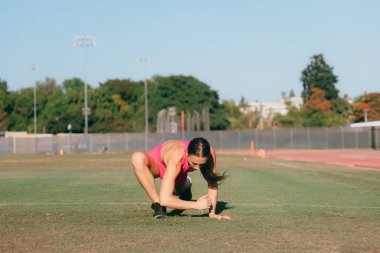 Isınma sırasında kalçalarını esneten bayan sporcu.