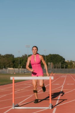 Bayan atlet engelin üzerinden atlamak üzere.