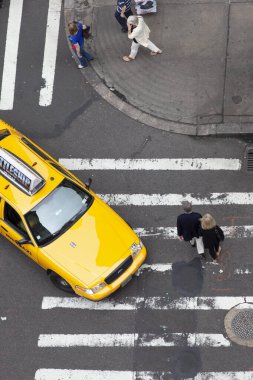 Top down view of yellow cab and pedestrians at NYC intersection clipart