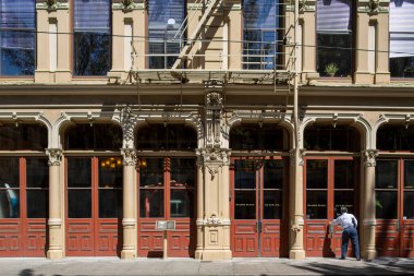 Adam kaldırımdan süslü binaya giriyor.