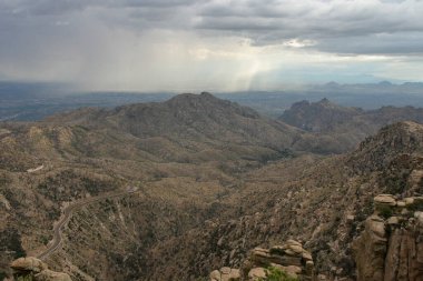 Rocky mountainous terrain and distant rainy weather clipart