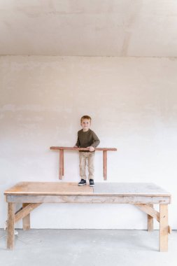 Bir anaokulu çocuğu inşaat halindeki bir evde oynuyor.