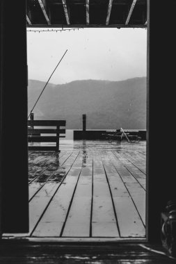 Bir yağmur fırtınası sırasında dağlarla dolu bir göldeki tek renkli rıhtım.