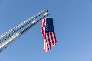 Amerikan bayrağı gökyüzünde bir itfaiye aracına asılmış.