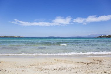 Kumlu sahili ve turkuaz suyu olan güzel bir deniz manzarası.