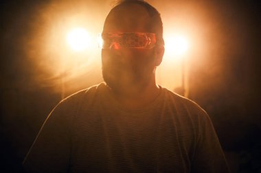 Parlak ışıklar altında kırmızı gözlüklü biri.