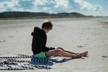 Slettestrand, Fjerritslev, Danimarka 'da plaj havlusunda oturan çocuk..