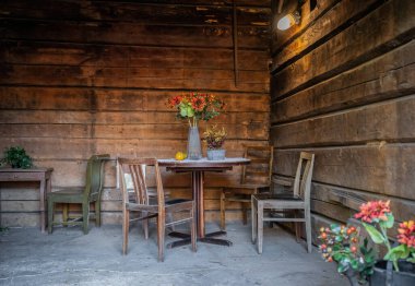 Eski ahşap sandalyeler ve içi tozla kaplı bir masa.