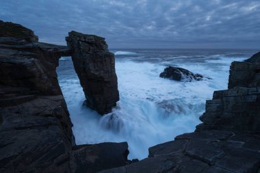 Dalgalar Yesnaby, Orkney, İskoçya 'da deniz yığınları etrafında akıyor