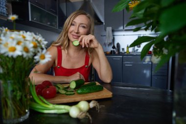 Kaygısız sarışın kadın evde sebzeli salata hazırlıyor.