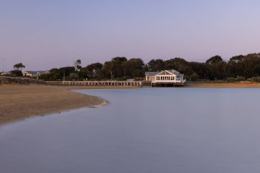 Calm riverbend and pier at sunset in Barwon Heads, Victoria clipart