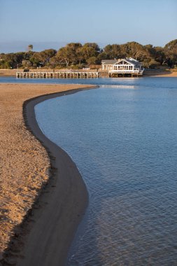 Barwon Heads 'de bir rıhtım ve kayıkhanesi olan huzurlu nehir kıvrımı