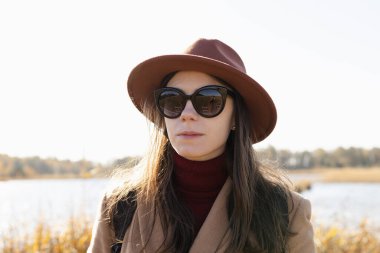 Şapkalı ve güneş gözlüklü genç bir kadının vesikalığı.