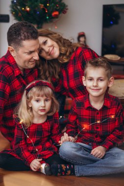 Evde aynı kıyafetleri giyen iki çocuklu bir aile.