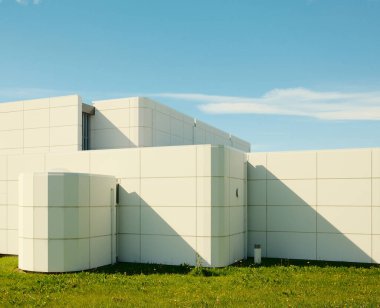 Çimlerin üzerinde beton kiremitler olan modern binanın ön cephesi