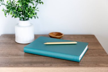 Teal planlayıcısı ve altın kalemi yeşillik ve kase ile ahşap bir masada