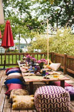 Yastık, çiçek ve ışıklarla bohem açık masa ayarı.