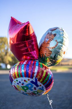 Colorful helium balloons, including Happy Birthday and tiger designs clipart