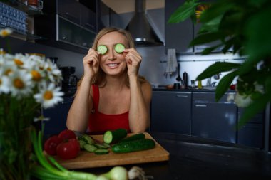 Kaygısız sarışın kadın sebzeli salata hazırlıyor.