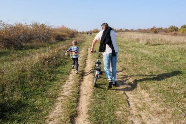 Neşeli anlar: baba oğluna bisiklet sürmede yardım eder