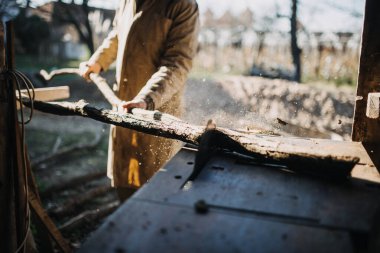 Yakından testereyle odun kesen bir adam..