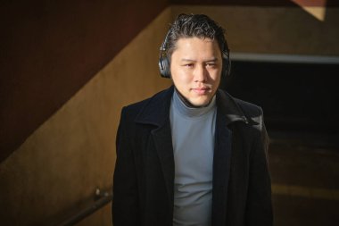 Modern bir binada kulaklık takan genç bir adam.