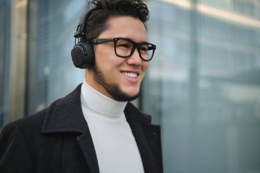 Kulaklıklı bir adam şehirde yürüyor.