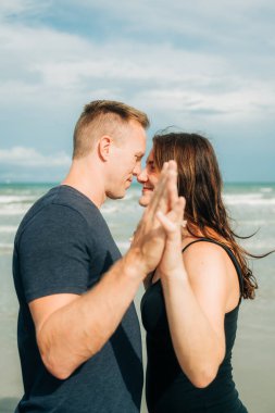 Bir çift kumsalda el ele tutuşurken özel bir anı paylaşıyor.