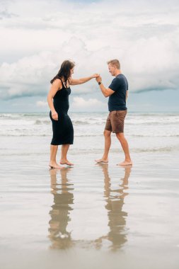 Kumsalda el ele tutuşan bir çift.