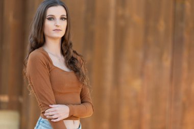 Kırsal ahşap arka planda poz veren sonbahar kıyafetli kadın..