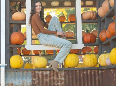 Neşeli bir pazarda balkabağı sergileyen gülümseyen bir kadın..