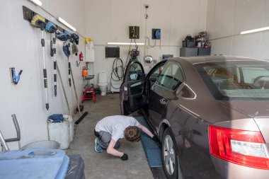 Side view of young male mechanic examining car at garage clipart