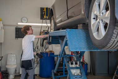 Side view of young male mechanic examining car at garage clipart