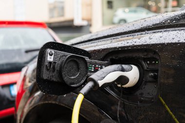 Yağmurlu bir günde elektrikli fişe takılı araba