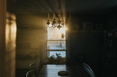 Güneş ışınları yemek odasının penceresinden ve avizesinden geçiyor.