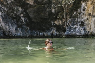 Kadın, doğayla çevrili bir nehirde banyo yapmaktan mutlu.