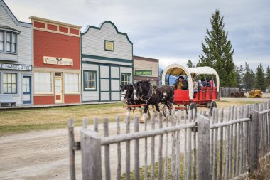 Ziyaretçiler, BC 'deki Fort Steele Hertiage Town' da at arabasıyla geziyorlar.