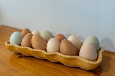 Ahşap bir yüzeyde seramik tepside çok renkli yumurtalar.