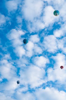 Mavi gökyüzünde bulutlar arasında uçan sıcak hava balonu. fotoğraf aşağıda.