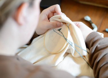 İşlemeli halkadaki kumaş parçasına gümüş iplikle dikilmiş bir insan..